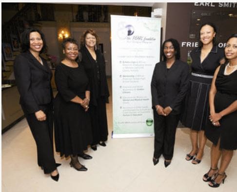 A group of women in black dress standing next to a sign.