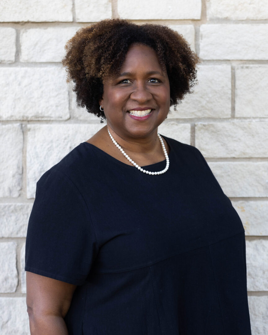 A woman standing in front of a brick wall.