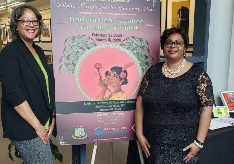 Two women standing next to a poster board.