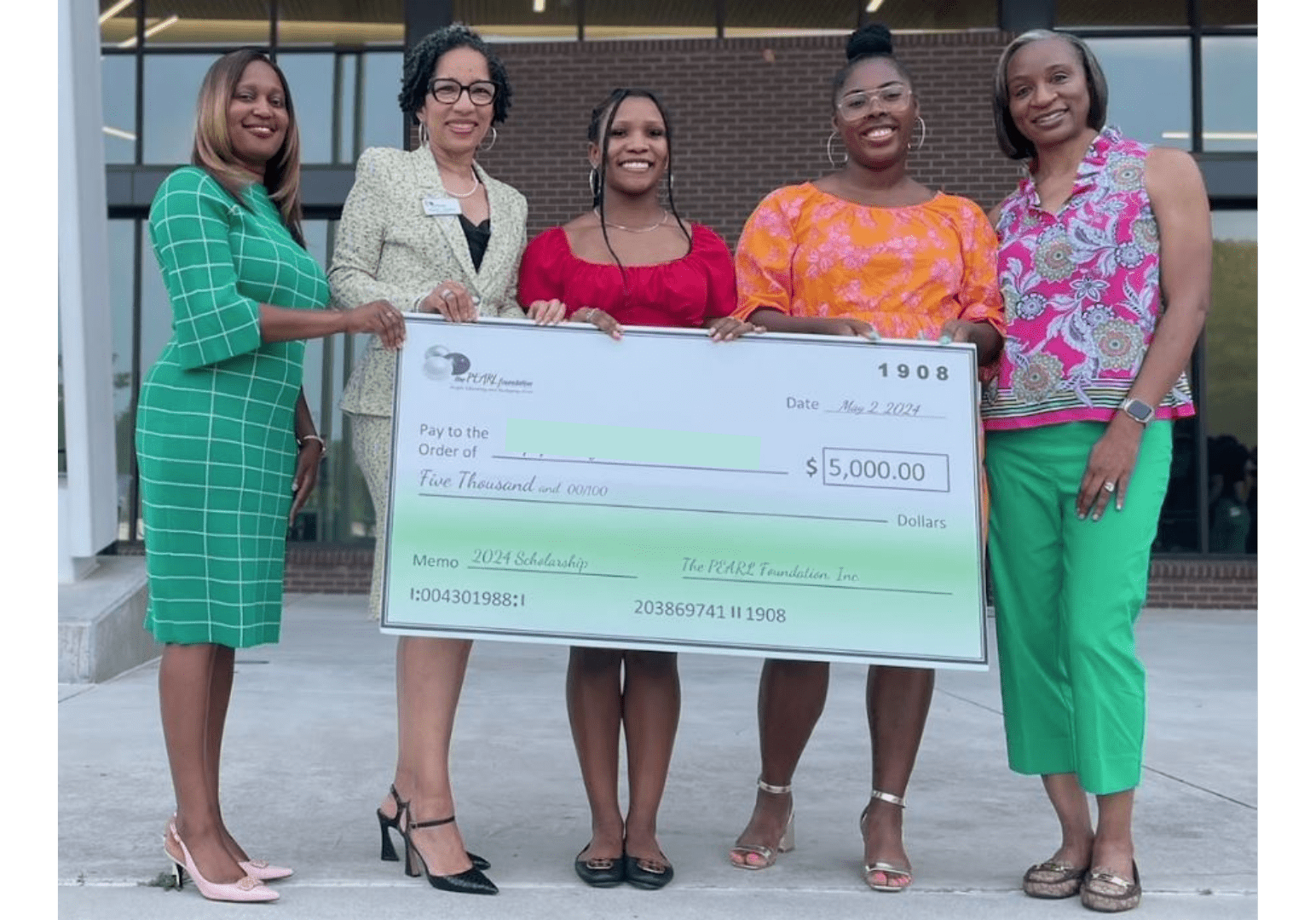 A group of women holding up a large check.