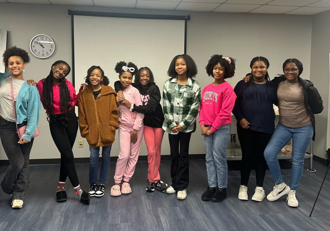 A group of young girls standing in front of a projector screen.